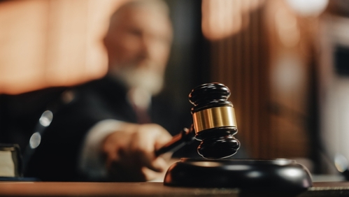 Close up of gavel with judge blurred in background.